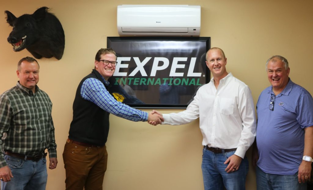 Employees Standing In Front of Expel Sign.