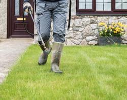 Employee Spraying lawn in Boots.