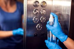 a woman sanitizing elevator buttons