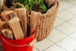 Firewood resting in a red bucket in a home.