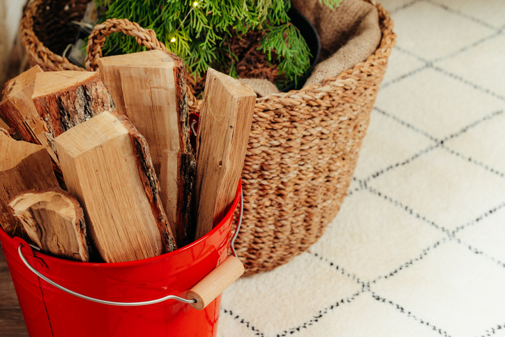 Firewood resting in a red bucket in a home.