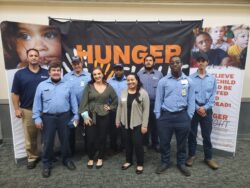 The McCall Pest & Wildlife team gathered in front of a fight hunger banner