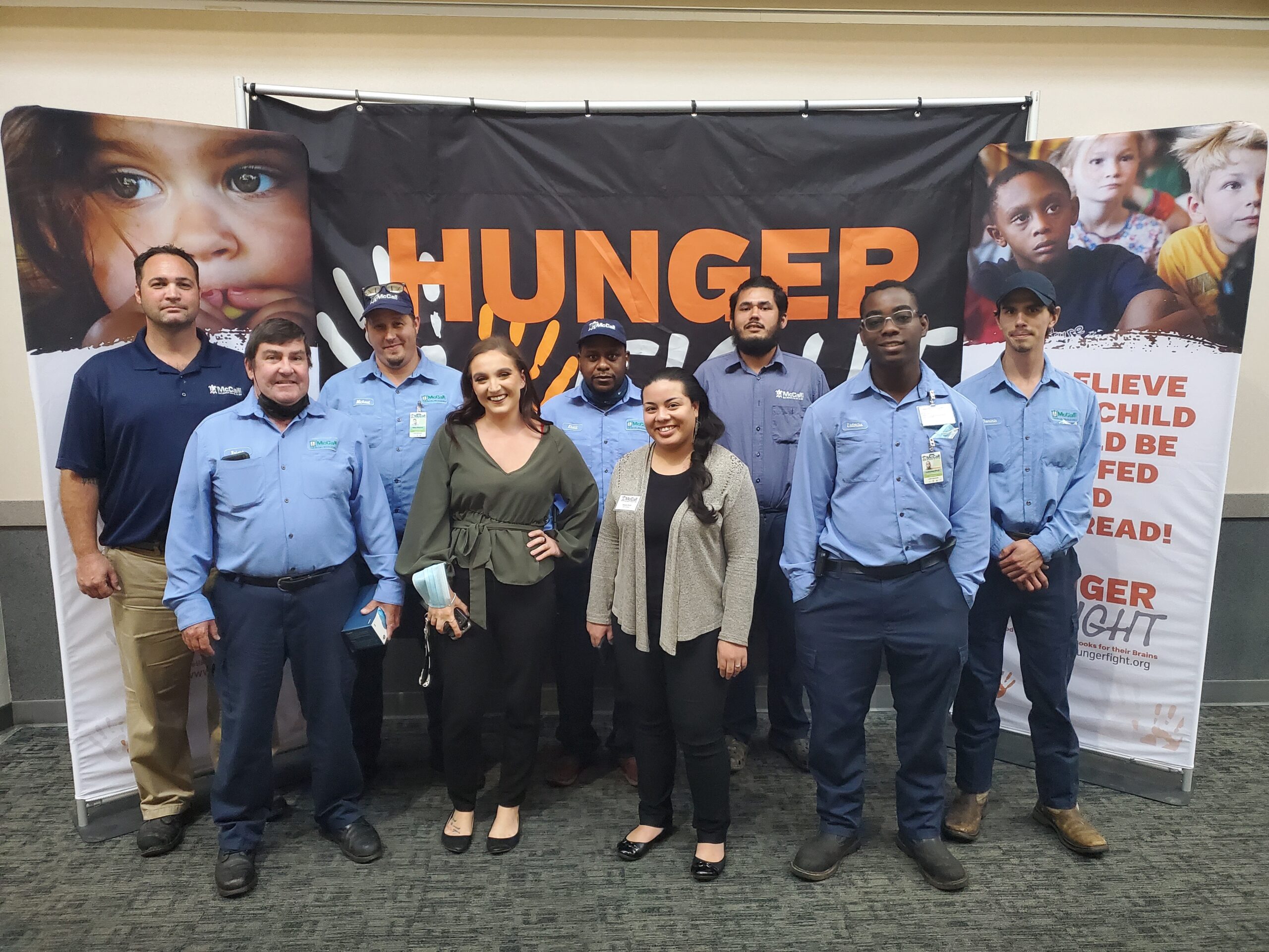 The McCall Pest & Wildlife team gathered in front of a fight hunger banner