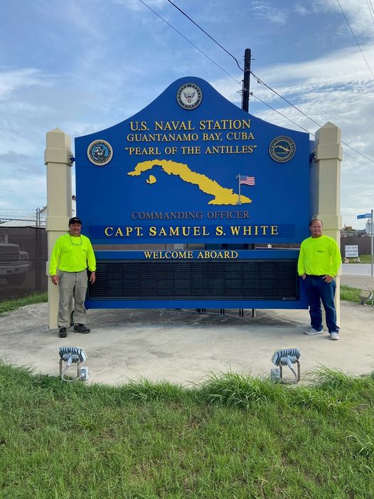 Two McCall Pest & Wildlife team members standing in front of the entrance to Guantanamo Bay in Cuba